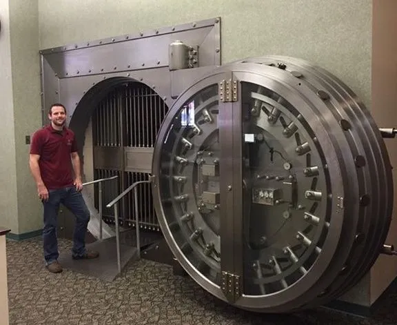 A man standing in front of a large metal door.