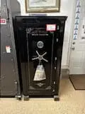 A black gun safe sitting in front of two doors.