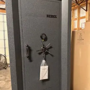 A large gun safe with a key and bottle of wine.