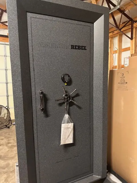 A large gun safe with a key and bottle of wine.