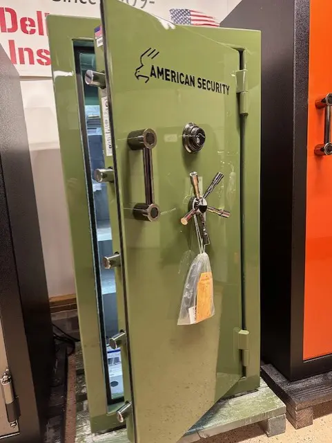 A green safe with keys hanging on the door.